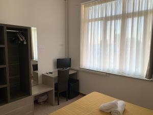 a room with a bed and a desk with a window at Hotel Virgilio in Taranto