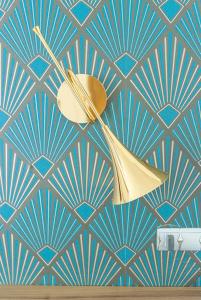 a lamp on a wall with a blue and white wallpaper at Carladez Cambronne in Paris