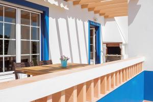 a balcony with a wooden table and a fireplace at Apartment Praia da Arrifana! in Aljezur