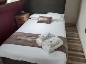 two beds in a hotel room with towels on them at High Tor Hotel in Matlock