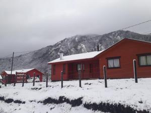 a red building in the snow with a mountain at Cabana Santa Matilde in Malalcahuello