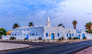 a white building with blue doors and a mosque at hotel arisha in Houmt Souk