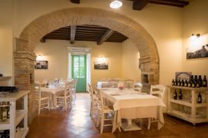 restauracja z białymi stołami i krzesłami oraz łukiem w obiekcie Borgo di Gallano w mieście Valtopina