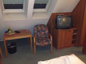 um quarto com uma televisão, uma cadeira e uma mesa em Hotel "Zur Panke" em Kolonie Röntgental