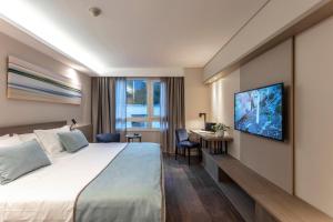 a hotel room with a bed and a tv on a wall at Huinid Obelisco Hotel in Buenos Aires