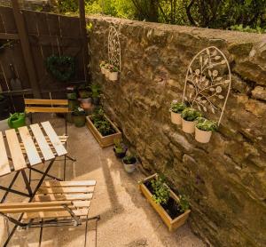een patio met stoelen en potplanten naast een stenen muur bij Jasmine Cottage Lastingham North Yorkshire in Pickering