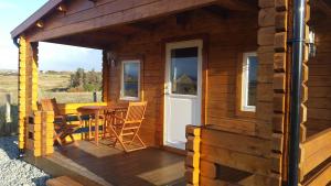 uma cabina de madeira com uma mesa e cadeiras num deque em Harlosh Log Cabins em Dunvegan