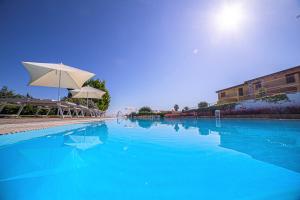 a swimming pool with blue water and umbrellas at Babai Village Resort in Tertenìa +38 photos