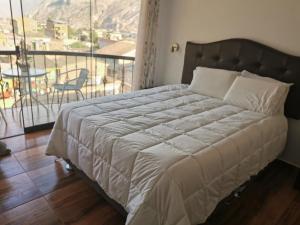 a bedroom with a bed and a balcony with a table at Hotel Quilla House 2 in Urubamba