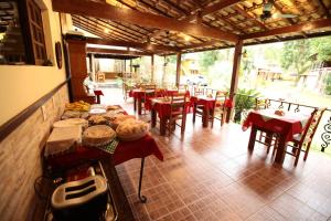 um restaurante com mesas e cadeiras vermelhas e cadeiras em POUSADA DAS ORQUIDEAS20 em Guapimirim