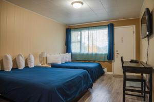 Habitación de hotel con 2 camas, escritorio y ventana en Lakeview Motel en Christina Lake
