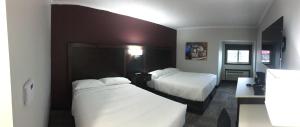 um quarto de hotel com duas camas com lençóis brancos em Homestead Inn & Suites em Vanderhoof
