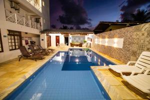 uma piscina com cadeiras e uma casa em Brisamar Hotel Pousada na Barra de São Miguel