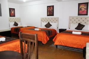 Habitación con 3 camas con sábanas de color naranja en Imperial Golden House Inn, en Cusco