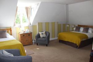 a bedroom with two beds and a chair and a window at Fairhaven Country Guest House in Goathland