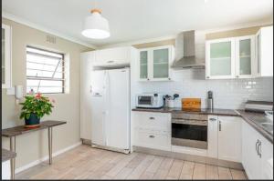 a kitchen with white cabinets and a white refrigerator at Safe, Accessible Venue Near Muizenberg for Accommodation and Events in Cape Town