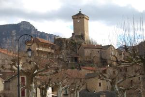 LA GRANGE TEMPLIERE 2018 في Peyreleau: مدينه فيها برج الساعه فوق جبل