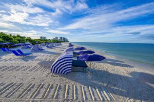 a row of beach chairs and umbrellas on the beach at Naples Grande Beach Resort in Naples