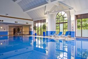 una piscina con sillas azules en un edificio en Holiday Inn Glasgow - East Kilbride, an IHG Hotel, en East Kilbride