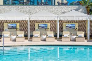 a pool with chairs and umbrellas next to a swimming pool at Naples Grande Beach Resort in Naples