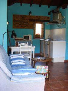 Habitación con cocina con sofá y mesa. en Apartamentos Rurales El Molín de Panizal en San Cosme