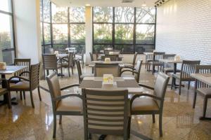 un restaurante con mesas, sillas y ventanas en Aparthotel Twin Towers en São Bernardo do Campo