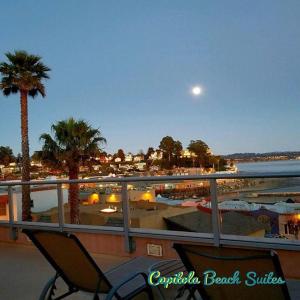 a balcony with a view of a beach with palm trees at Capitola Beach Suites in Capitola