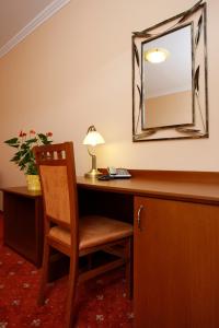 Zimmer mit einem Schreibtisch, einem Stuhl und einem Spiegel in der Unterkunft Hotel Majolika in Modra