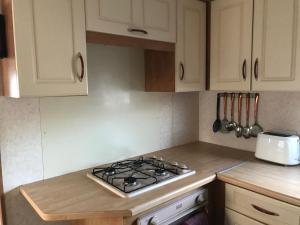 a kitchen with white cabinets and a stove top oven at 8 Berth on Coral Beach (Westmorland) in Ingoldmells