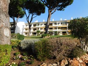 un grand bâtiment blanc avec des arbres et des buissons dans l'établissement Sol Nascente Garden, à Vilamoura
