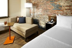 a room with a bed and a couch and a brick wall at The Lodge at Duke Medical Center in Durham