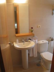 a bathroom with a sink and a toilet and a mirror at Hostal Ciudad de Cáparra in Carcaboso