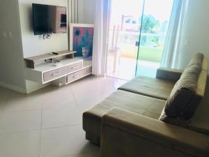 Il comprend un salon doté d'un canapé et d'une télévision à écran plat. dans l'établissement Apartamentos Mediterrâneo Home Club, à Bombinhas