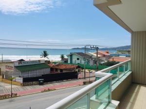 a balcony with a view of a city and the ocean at Apartamentos Mediterrâneo Home Club in Bombinhas