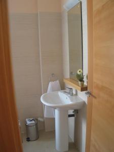 y baño con lavabo blanco y espejo. en Hostal Ciudad de Cáparra, en Carcaboso