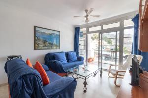uma sala de estar com um sofá azul e uma televisão em Flatguest Mogan + Beach + 2Bdr + Terrace em Mogán