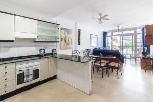 uma cozinha com armários brancos e uma mesa com cadeiras em Flatguest Mogan + Beach + 2Bdr + Terrace em Mogán