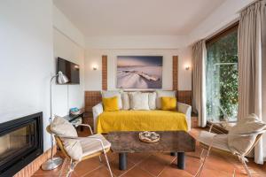 タヴィラにあるPedras del Rei, Nature and Beach Apartmentのベッドルーム(黄色のベッド1台、暖炉付)