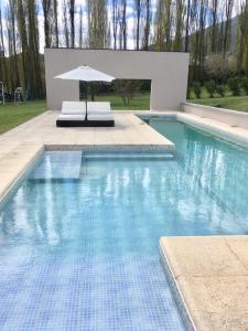 a swimming pool with a table and an umbrella at La Aguada in El Bolsón