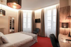 Una habitación de hotel con una cama y dos ventanas. en Hôtel Montaigne, en Sarlat-la-Canéda