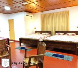 - 2 lits dans une chambre avec des chaises et des tables dans l'établissement City Centre Lodge, à Anurâdhapura