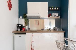 a kitchen with white cabinets and a blue wall at Appartement entier, proche Part-Dieu Checkin 24H in Villeurbanne