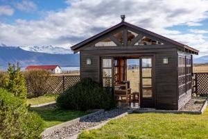 una pequeña cabaña en un patio con montañas al fondo en Puerto Bories House, Country Houses in Patagonia, en Puerto Natales