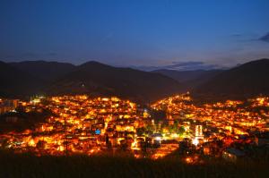 a city lit up at night with mountains at Palyongov Guest House in Chepelare +11 photos