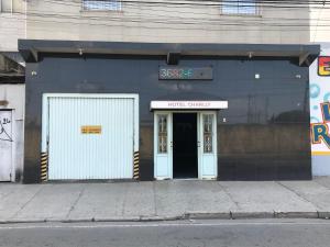 a building with two white doors on a street at Hotel Charlly in Osasco