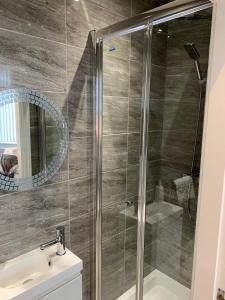 a bathroom with a shower with a sink and a mirror at Priory Suites in Liverpool