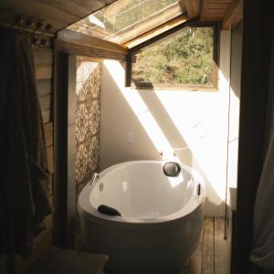 a bath tub in a bathroom with a window at Reserva Três Picos Chalés in Nova Friburgo