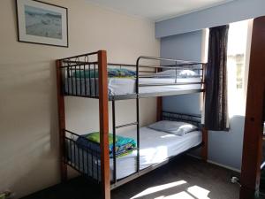 two bunk beds in a room with a window at Annies Nirvana Lodge, Golden Bay YHA in Takaka