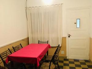 una habitación con una mesa roja con sillas y una puerta en Casa en el centro para 6 personas en Villa Cura Brochero