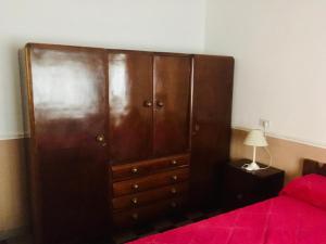 un gran armario de madera en un dormitorio con cama roja en Casa en el centro para 6 personas en Villa Cura Brochero
